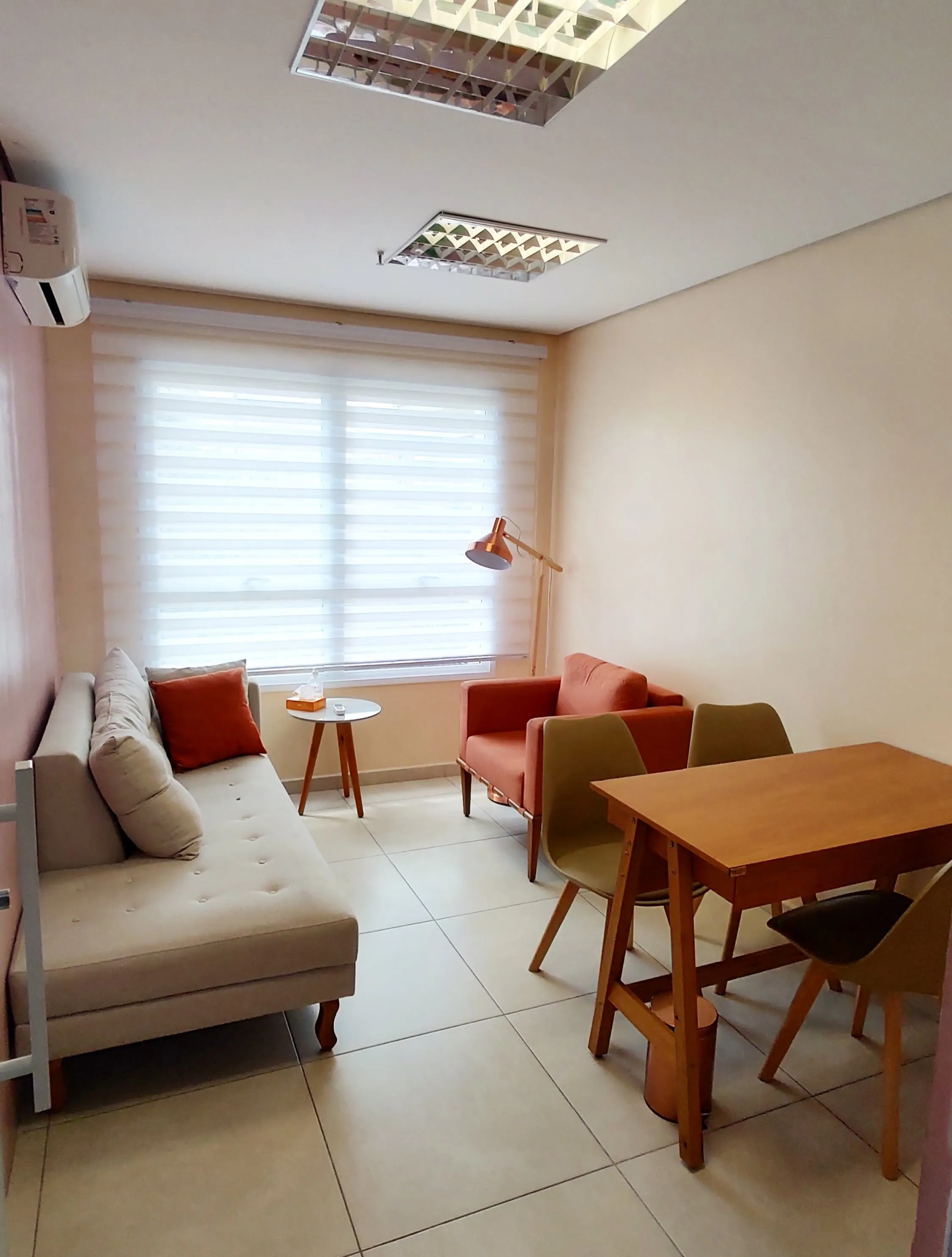 Sala Rosa com divã, poltrona, luminária de piso e mesa com cadeiras