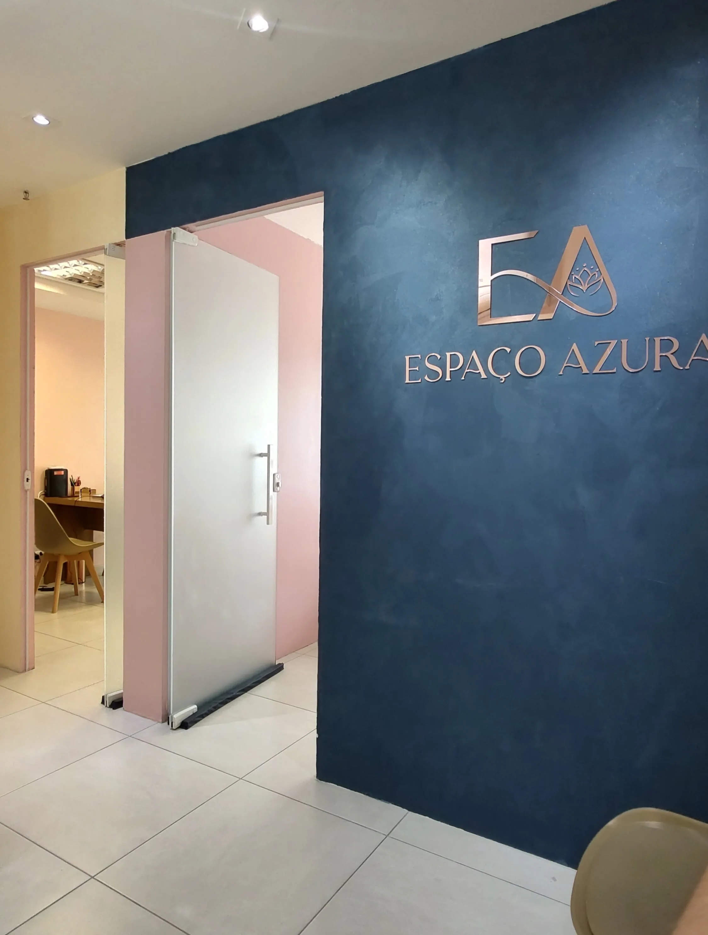 Recepção do Espaço Azura, com o logotipo em parede azul e a entrada das salas